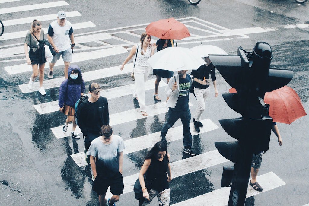 people walking across street in rain with umbrelllas