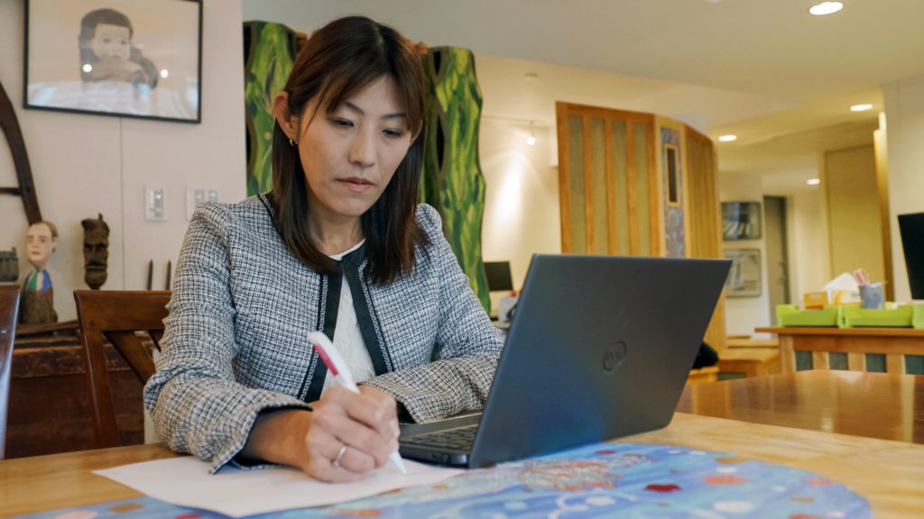 Asian woman writing with laptop
