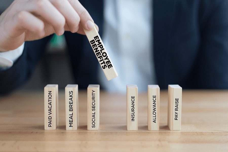 Hand lining up wooden blocks with different employee benefits printed on each one.
