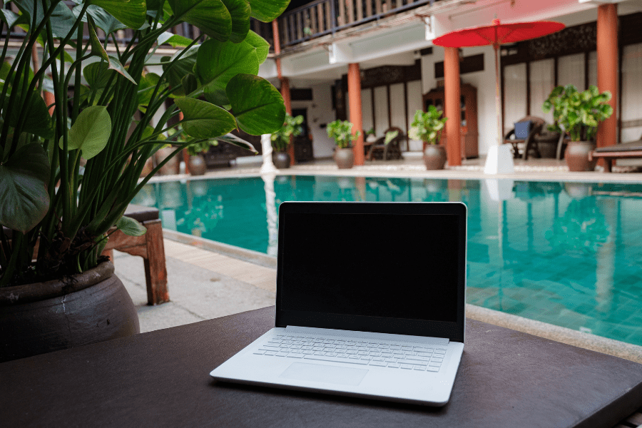 laptop of a remote digital nomad against the backdrop of a beautiful pool in a hotel