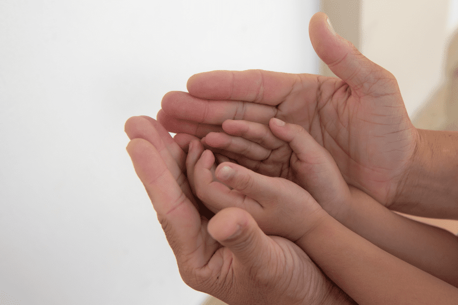 a parent's hands protecting a child's hands