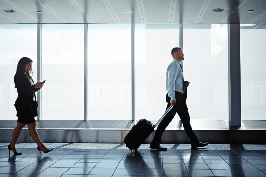 two businesspeople walking down an airport corridor while on a business trip