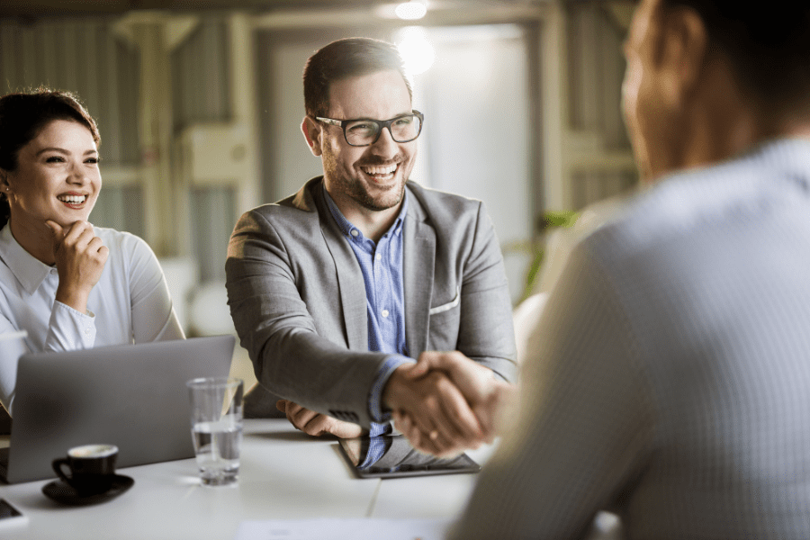 hiring managers smiling and shaking hands with a candidate