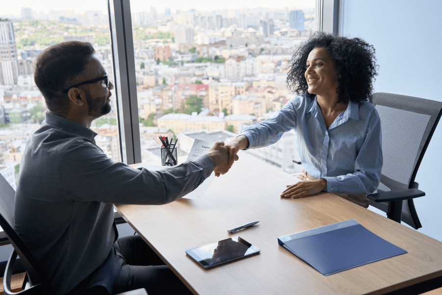 Male Hiring manager shaking hands with African female candidate during a job interview
