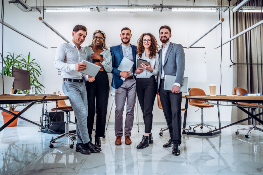 a group of five IT professionals from LATAM holding electronic gadgets and posing for a picture