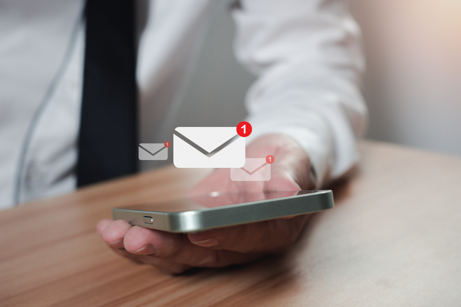 an employee holding a smartphone with three digital email notification symbols