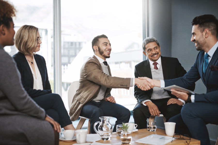 two businessmen shaking hands in a group