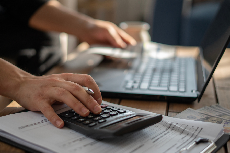 a hiring manager using a calculator and a laptop