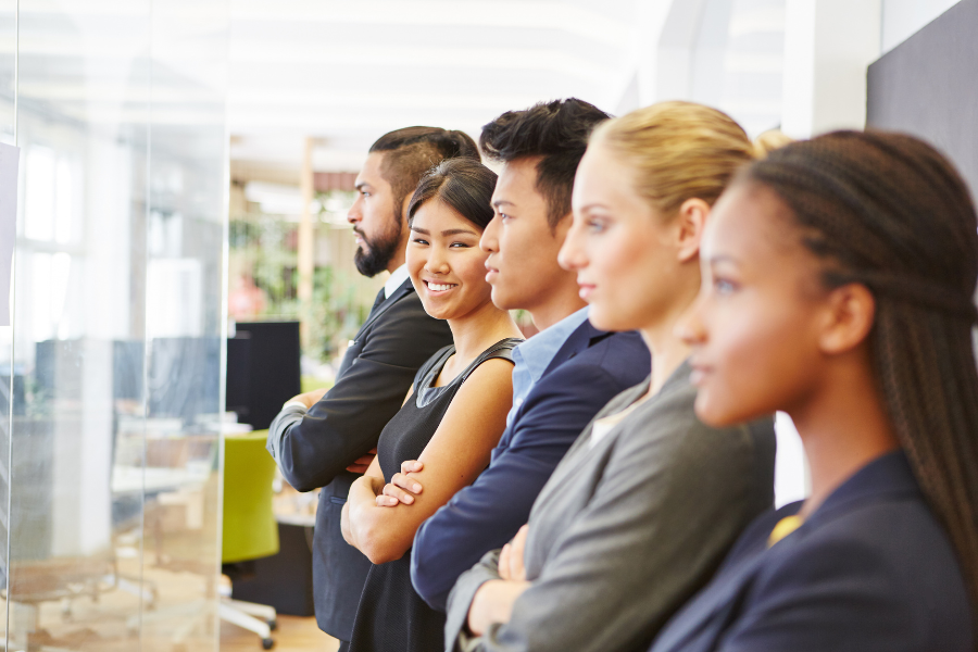 a group of 5 employees with one looking at the camera