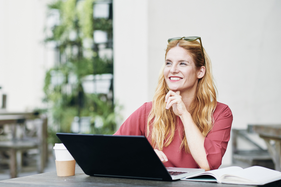 a female freelancer working remotely on a laptop at a coffee shop