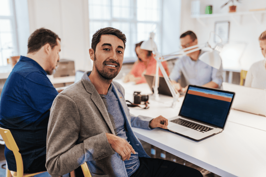 a Latino man smiling at the camera while working in an office