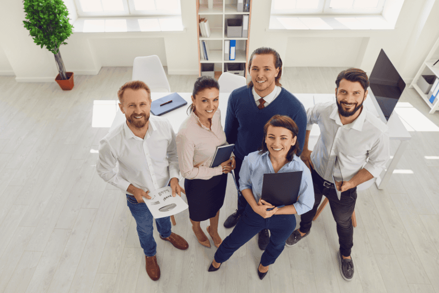 a group of five professional employees looking upward and smiling