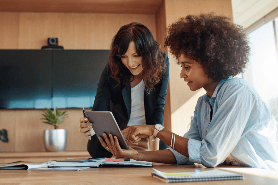 two female colleagues discussing employee benefits while looking at an iPad