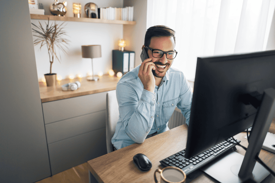 Remote working employee talking on phone while looking at monitor