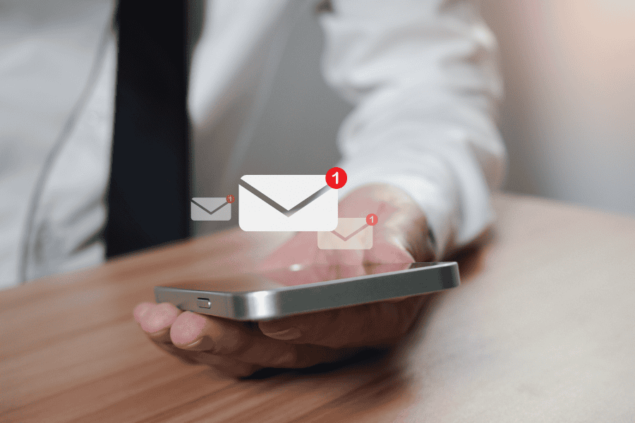 an employee holding a smartphone with three digital email notification symbols