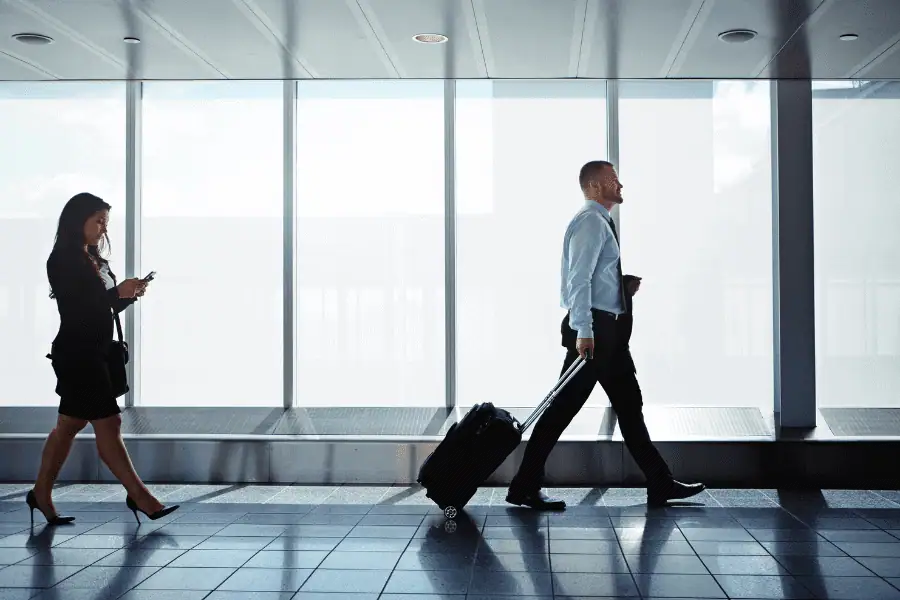 two businesspeople walking down an airport corridor while on a business trip
