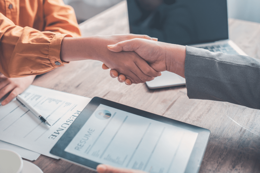 an HR manager shaking hands with a job applicant