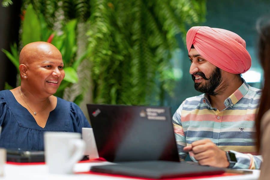 a woman talking to a man in front of a laptop