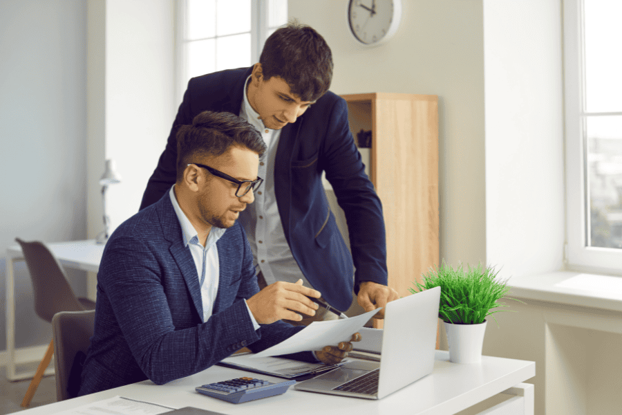 Payroll specialist giving directions to his assistant while working.