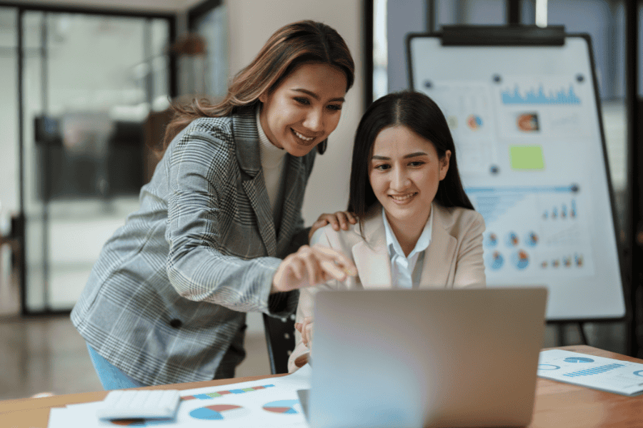 Two female colleagues looking at a payroll platform on a laptop.