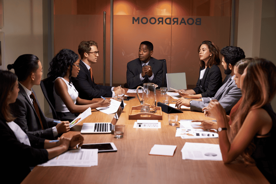 nine colleagues sitting in a board room for a meeting