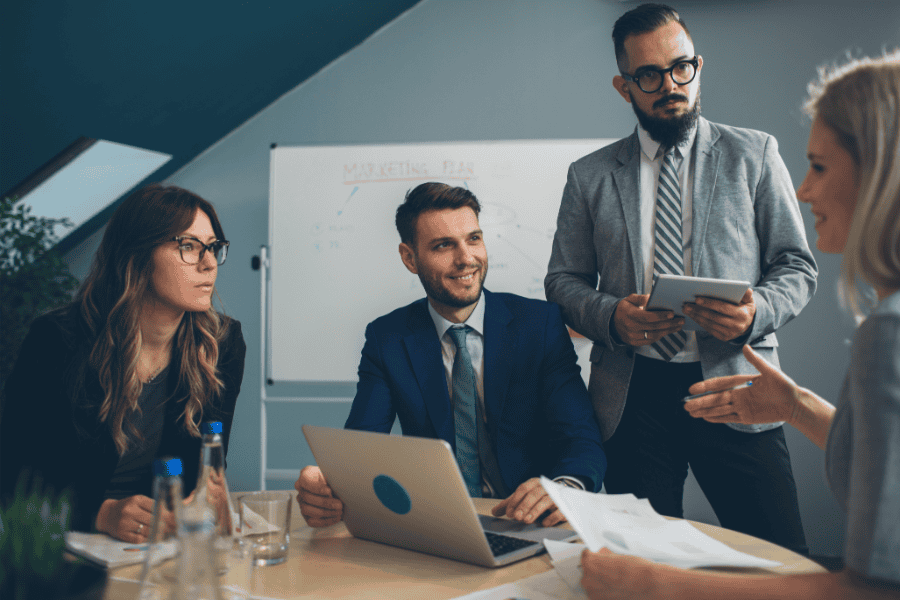 A group of 4 business people discussing in a conference room.