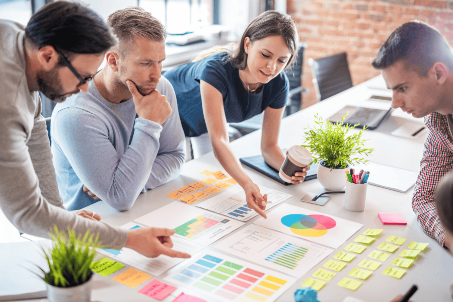 four colleagues examining charts and graphs on a table
