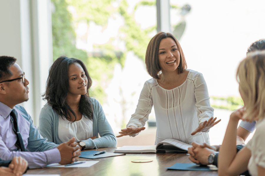 a businesswoman speaking to colleagues at a table
