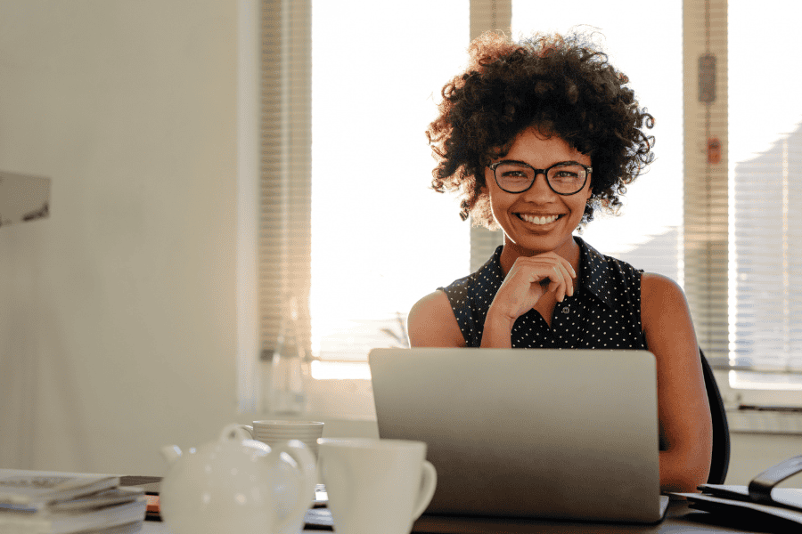 a female tech talent smiling while working on a laptop