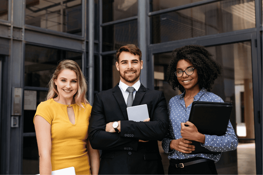 three diverse colleagues standing together in front of an office building