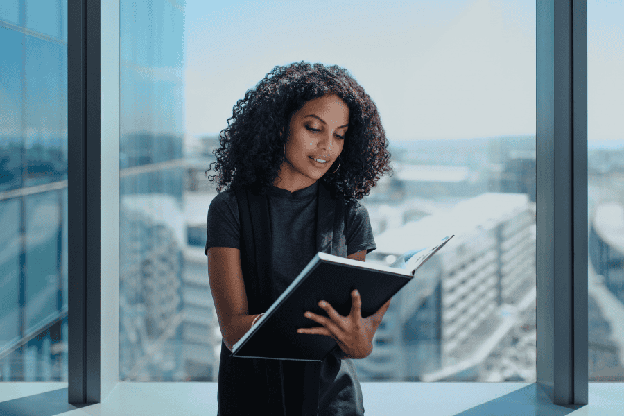 a female professional looking at her notebook next to a window