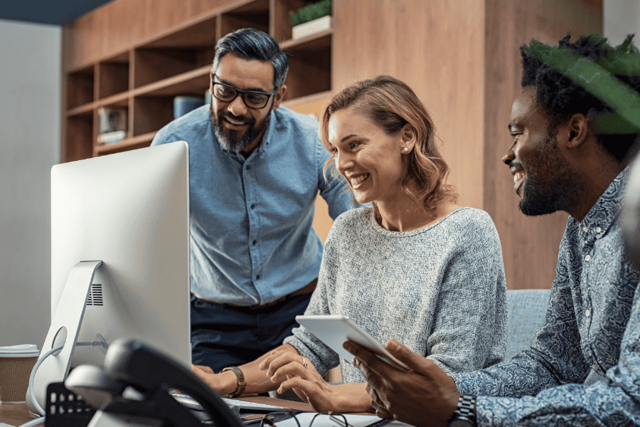 Three diverse colleagues working together at a desk.