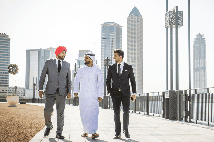 Three diverse businessmen walking and discussing about RHQs in Saudi Arabia.