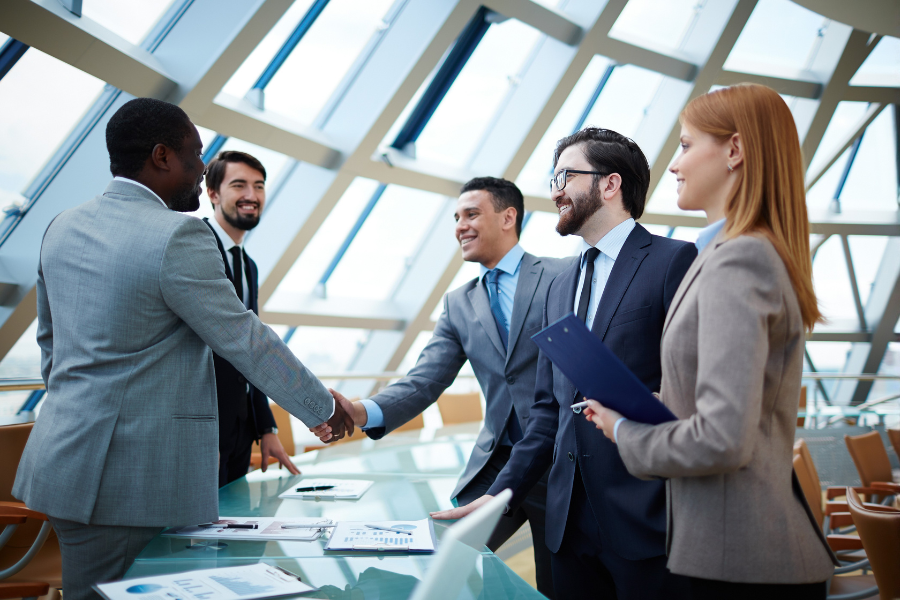five professionals standing together while two of them shake hands