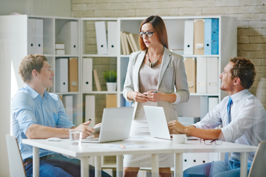 two professional men looking up at a professional woman talking