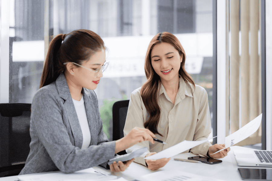 two professional women reviewing APAC expansion documents at a table
