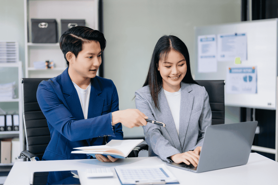 Two young professionals checking Singapore's 2026 budget on a laptop.