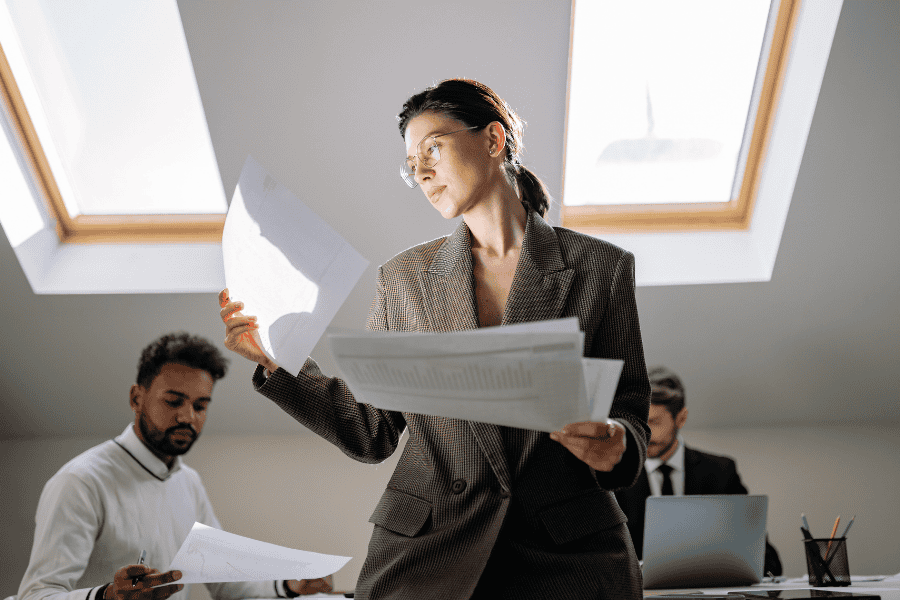 a professional woman reviews expansion plan paperwork in an office while colleagues work in the background