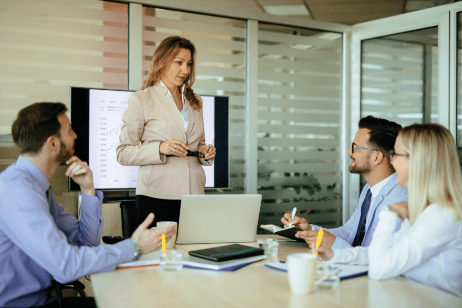 a professional woman presenting a Canada setup guide to three colleagues
