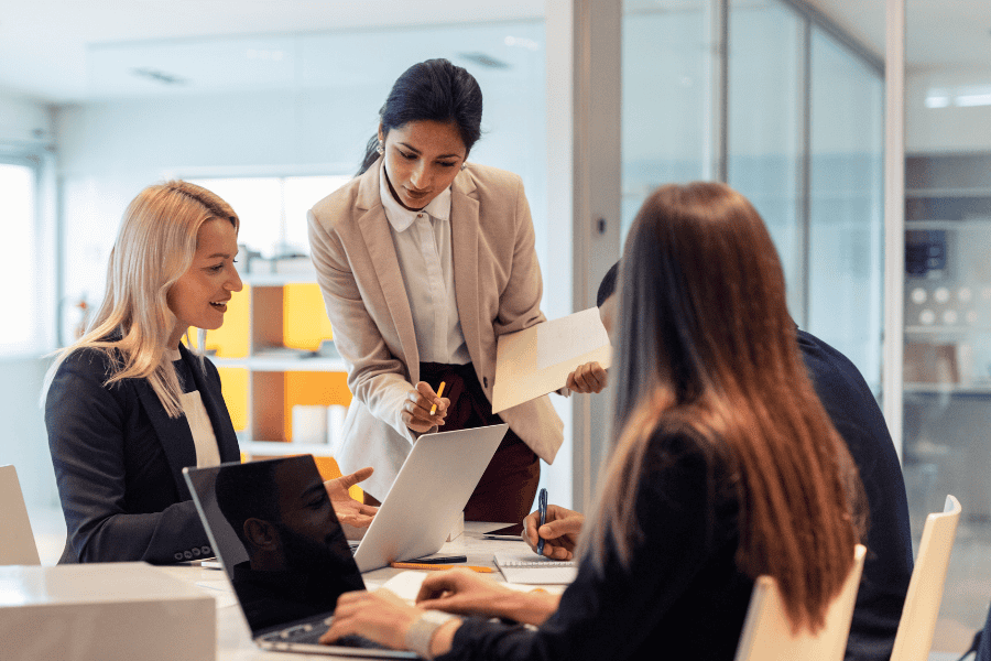 a professional woman reviewing a document with three other colleagues inside an office
