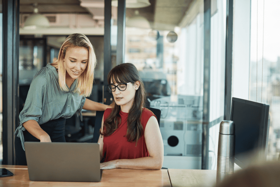 two professional women looking at a laptop together