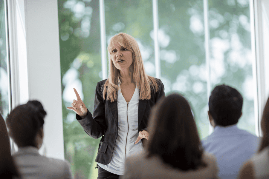 a professional woman talking in front of colleagues