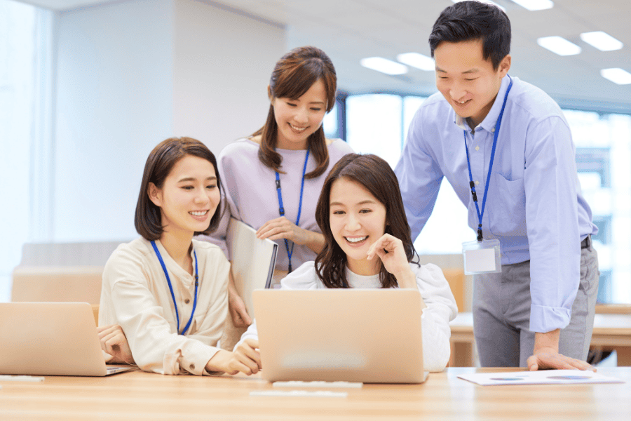 Team of professionals working together on a laptop in a modern office.