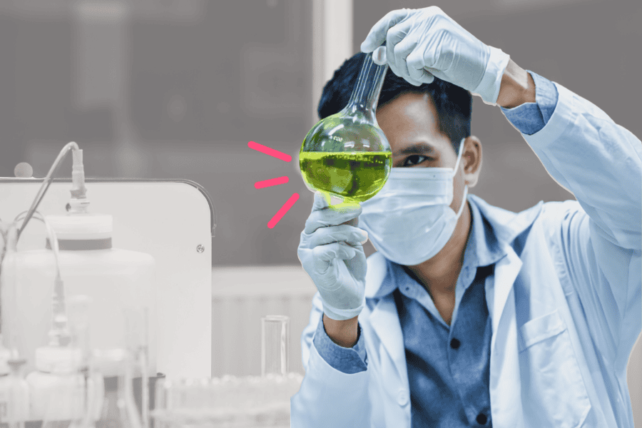Scientist examining a green liquid in a laboratory setting.