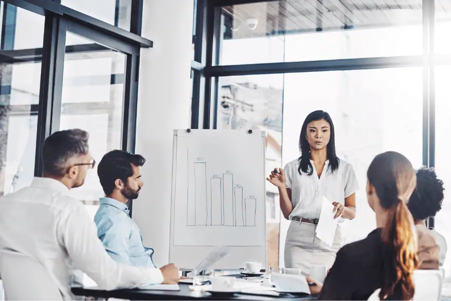 Businesswoman presenting tax model comparison to diverse team in modern office.
