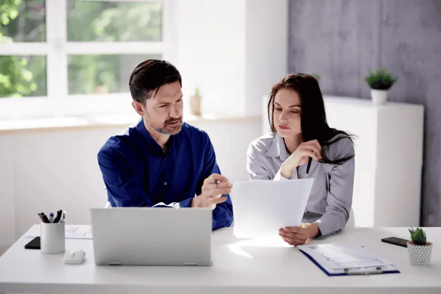 Two professionals reviewing documents in a modern office setting.