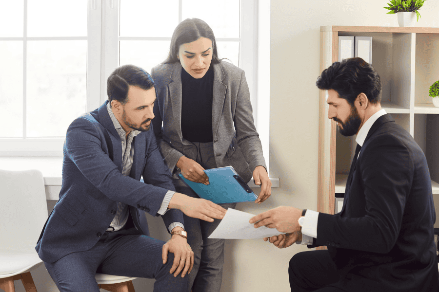 Three professionals reviewing documents in a bright office.