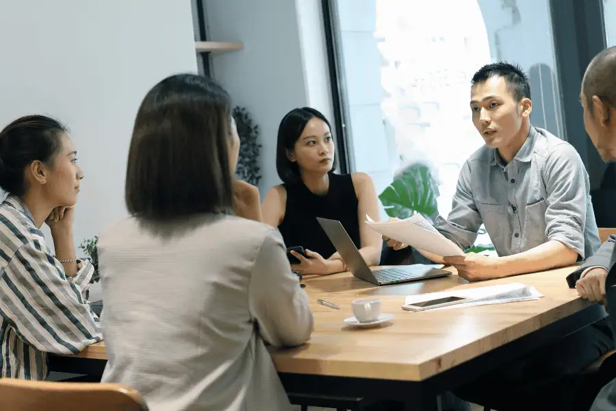 Team discussing factory setup and relocation in Thailand during a business meeting.